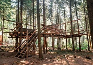 Ein großes Baumhaus in einem lichten Wald.