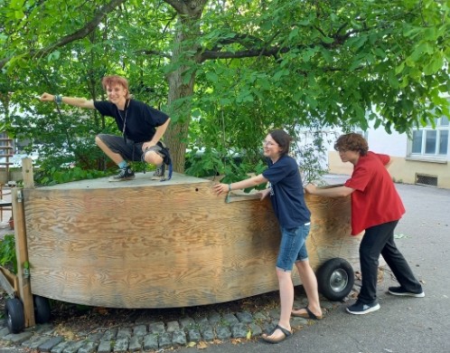 Unsere FÖJies schieben gemeinsam einen Holzwagen.